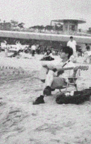Yinghao Tang playing guitar by the sea